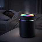 Black humidifier with colorful lights on a nightstand next to a person sleeping in bed.